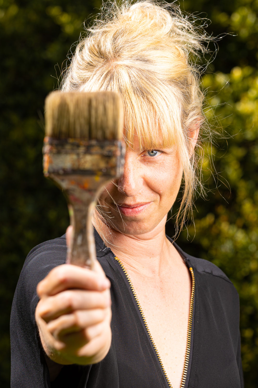 PORTRAIT_CAROLE_BOUTIER_OLD_AND_YOU_PINCEAU_PEINTURE Portrait de Carole Boutier avec un pinceau dans la main tendue vers l'objectif photo, pour présentation page "Qui suis_je ?" sur le site Old and You